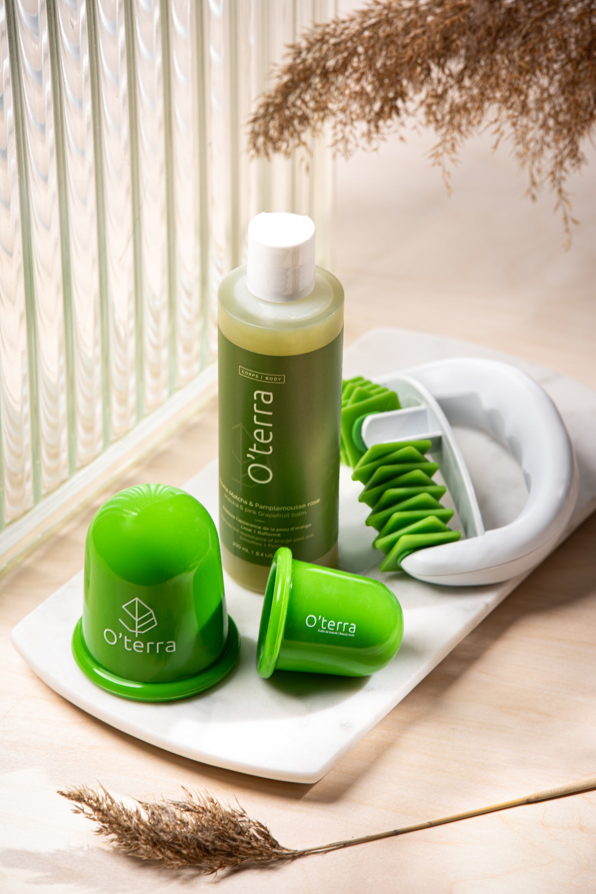 L'ensemble complet O'terra comprenant le baume au matcha, la roulette de massage et le duo de ventouses en silicone sur un plateau de marbre.